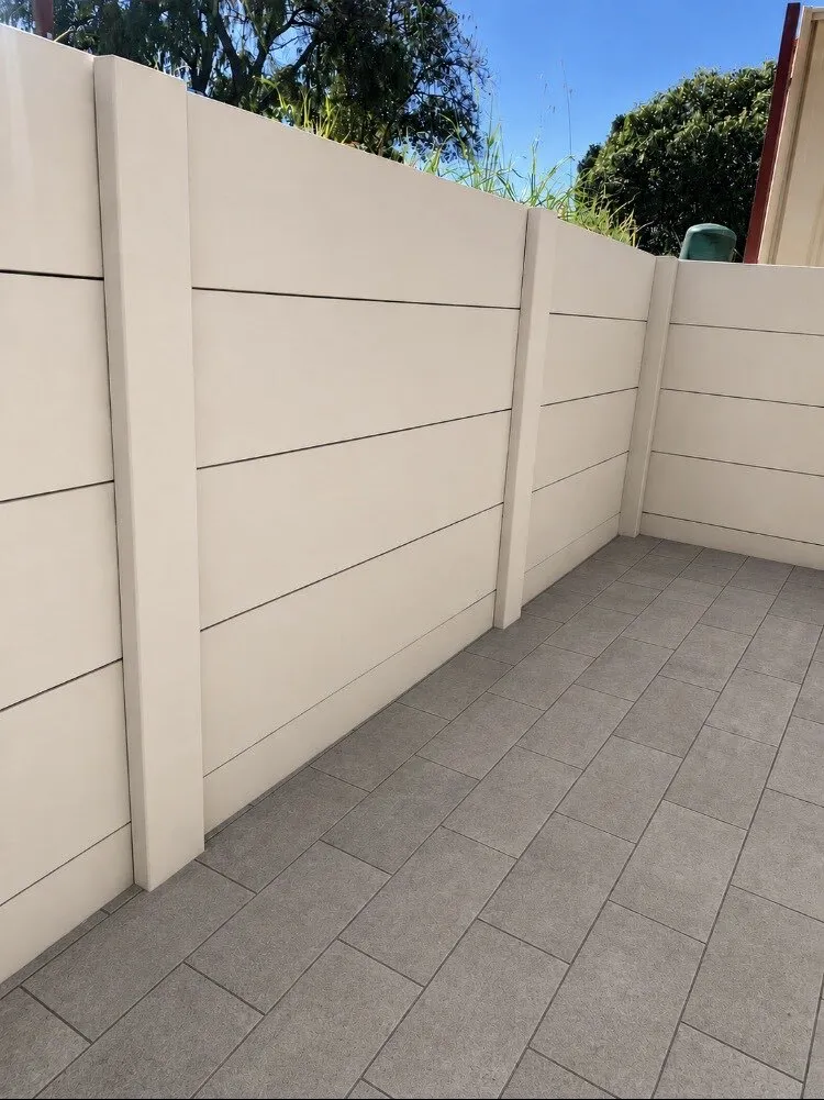 Cream panel retaining wall with a fence above a paved Perth courtyard